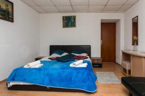 Ein Schlafzimmer mit einem Bett, einem Nachttisch, einem Schreibtisch, einem Stuhl und einer Tür.