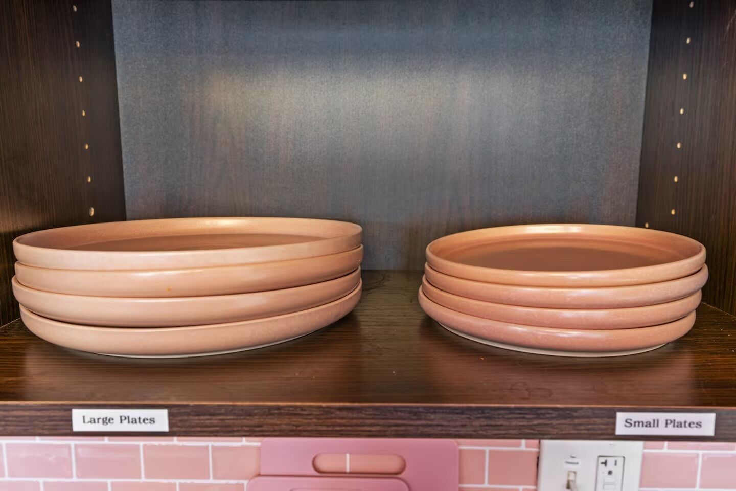Una cocina con dos pilas de platos etiquetadas como 'Large Plates' y 'Small Plates' sobre una encimera de madera.