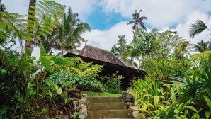 Un jardín tropical que conduce a un edificio con techo de tejas.