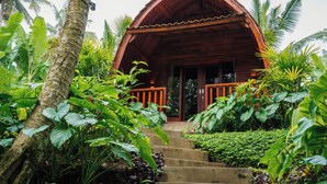 Un edificio de madera con porche, rodeado de exuberante vegetación tropical.