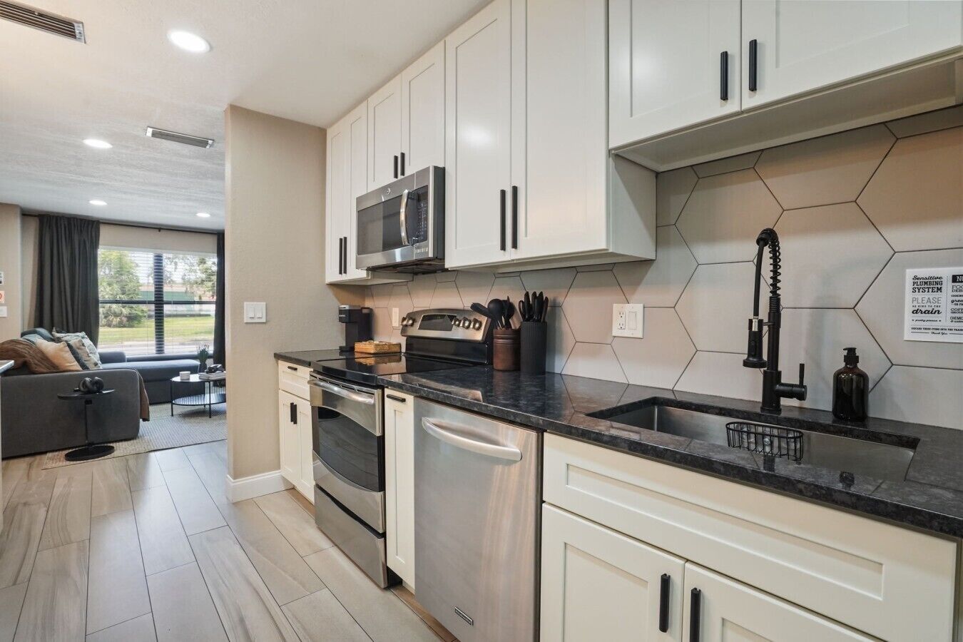A modern kitchen with white cabinets, stainless steel appliances, and a black countertop.