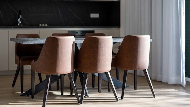 A modern dining area with a rectangular table and six chairs, a black marble backsplash, and a kitchen in the background. - Luxury Living at Horizon Retreat - Two Bedroom Apartment (Marina)