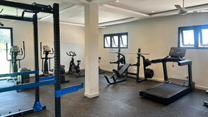 A gym with exercise equipment, a treadmill, and a mirror.