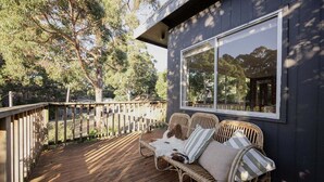 A wooden deck with wicker furniture and a large window. - Stewie's Nest - Port Arthur Shack with fire pit (Tasman)