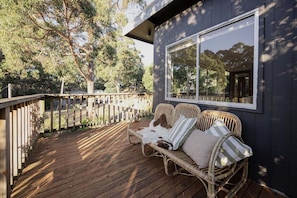 A wooden deck with wicker furniture and a large window.