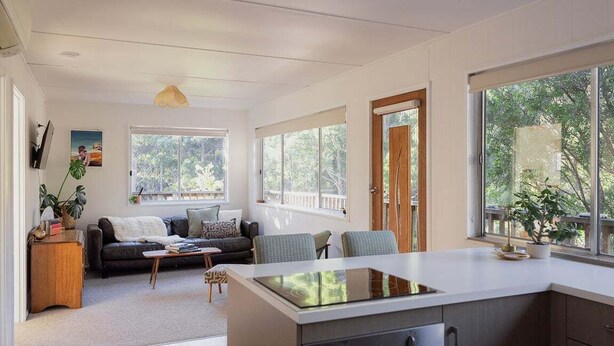 A modern kitchen with a central island, large windows, and a cozy seating area with a sofa and chairs. - Stewie's Nest - Port Arthur Shack with fire pit (Tasman)