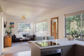 A modern kitchen with a central island, large windows, and a cozy seating area with a sofa and chairs.