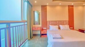 Habitación de hotel con una cama grande, una mesita de noche, un espejo y un balcón con barandilla.