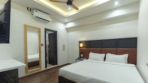 A hotel room with a bed, bedside table, nightstand, mirror, wardrobe, and ceiling fan.