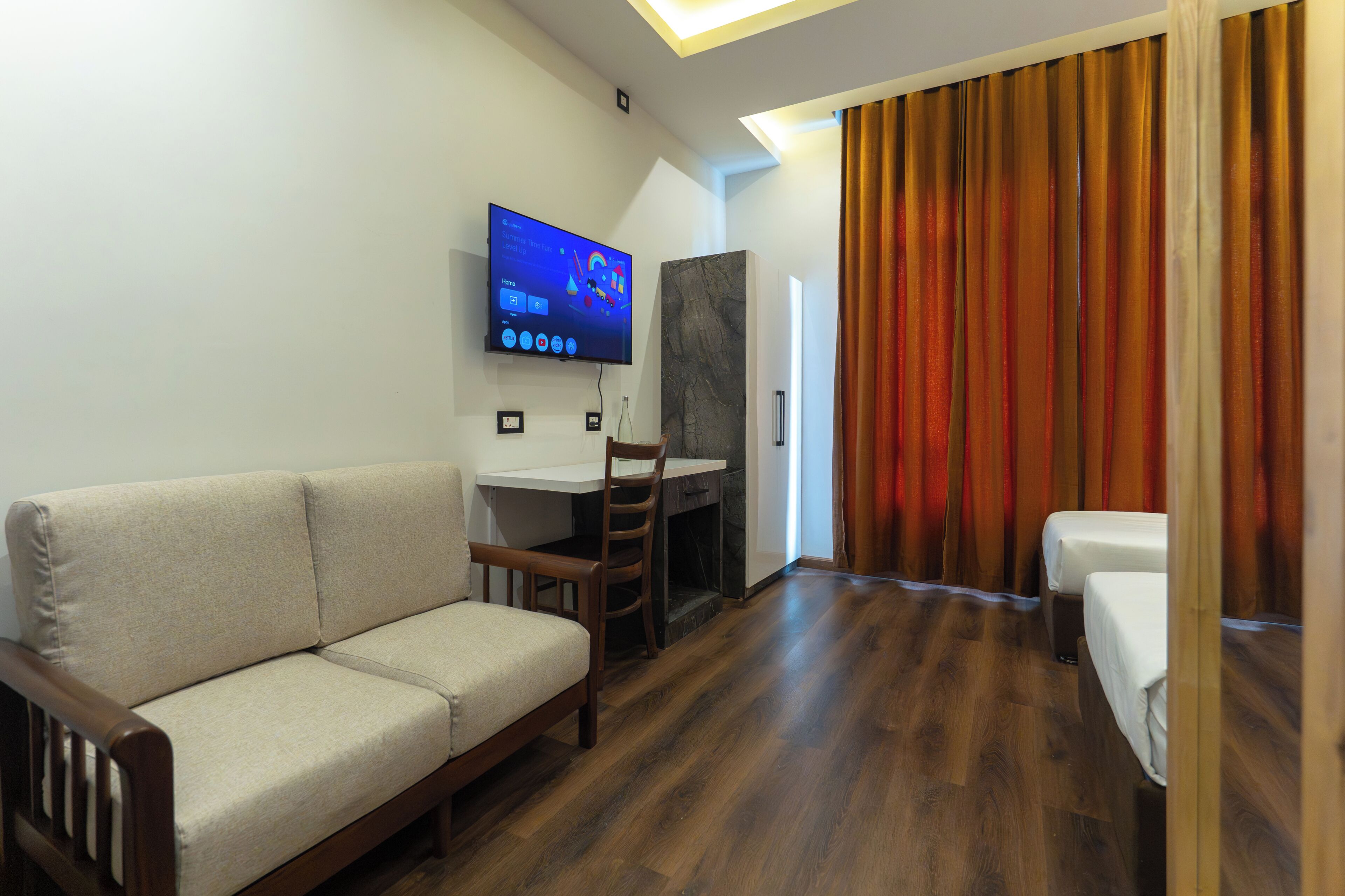 Ein Hotelzimmer mit Sofa, Schreibtisch, Fernseher und Bett.