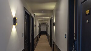 A hotel hallway with doors, light fixtures, and a carpeted floor.