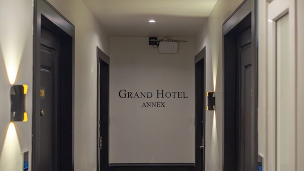 A hallway with doors, a sign reading 'Grand Hotel Annex,' and a ceiling-mounted projector.