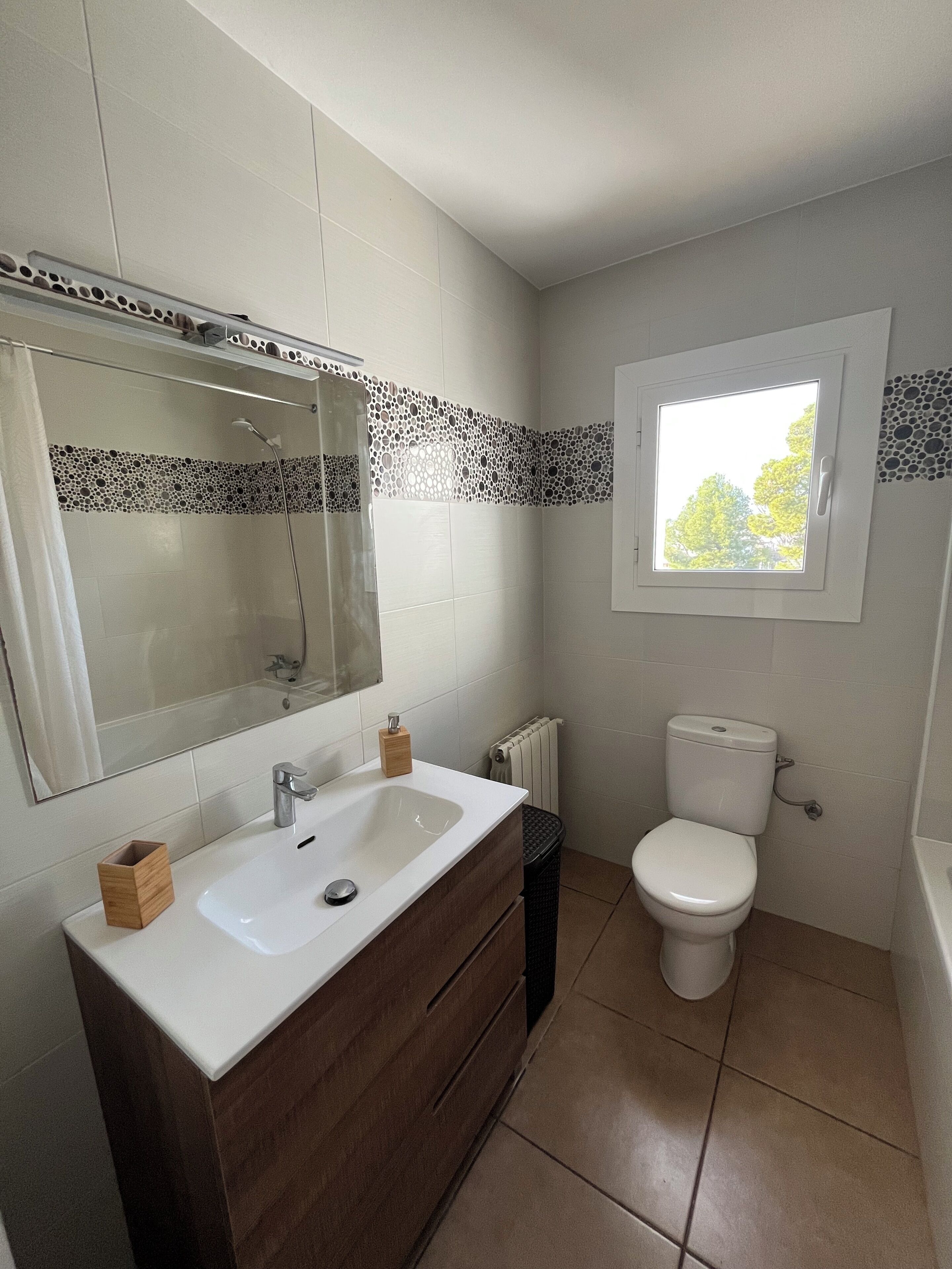 Ein Badezimmer mit Waschbecken, Spiegel, Toilette und Fenster.