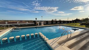 A clear blue swimming pool with steps leading into it, surrounded by a landscaped area with a view of the sky. - Beach House. Beachfront Apartment (Creixell)