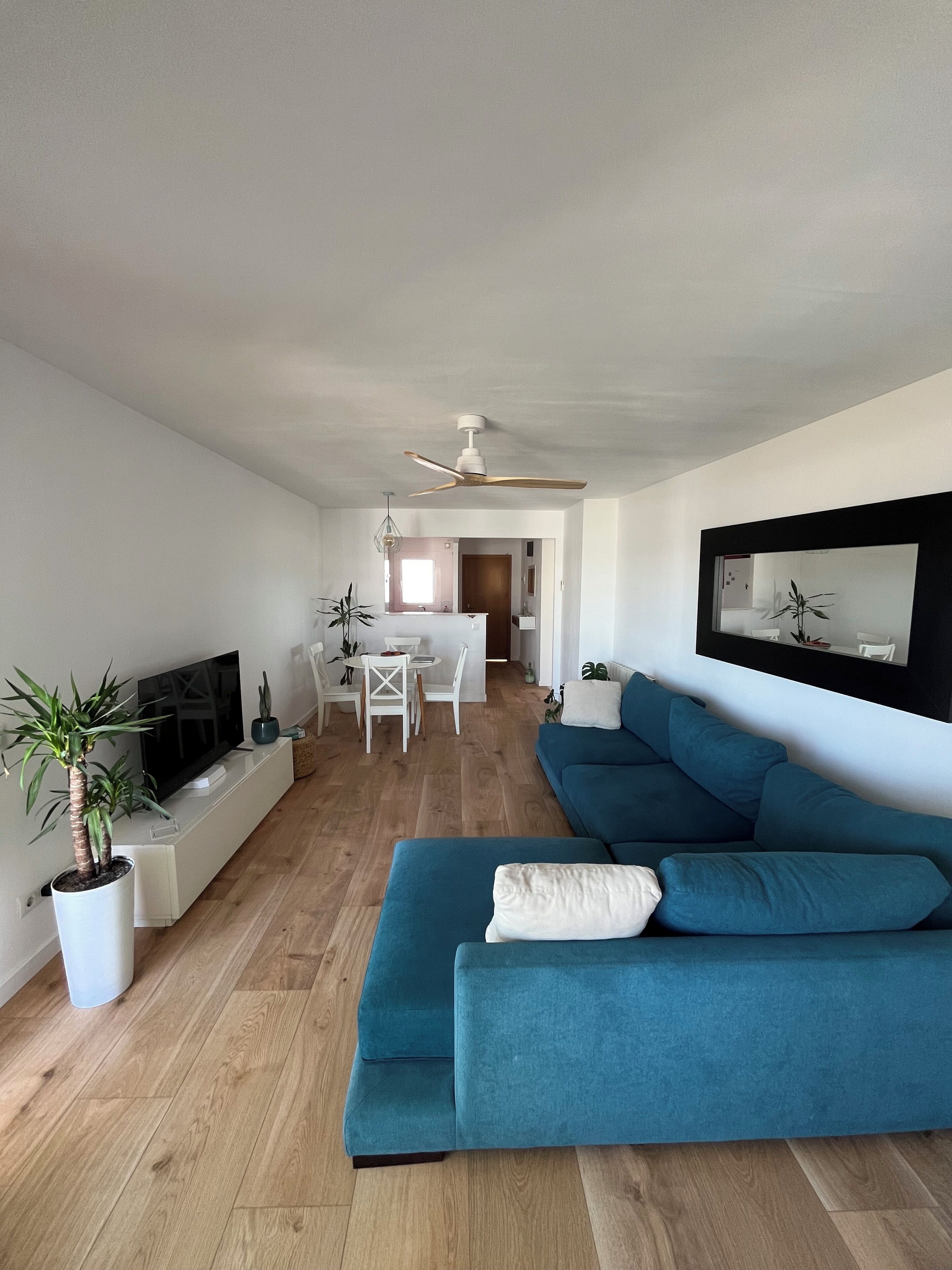 Un salon moderne avec un canapé bleu, un téléviseur à écran plat et un coin repas comprenant une table et des chaises.