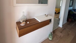 A bathroom with a large mirror, a wooden vanity, a decorative wall light, and a potted plant. - Beach House. Beachfront Apartment (Creixell)