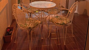 A balcony with a round table and chairs, overlooking a sunset over the sea. - Beach House. Beachfront Apartment (Creixell)