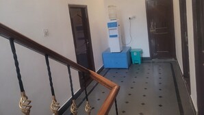 Un couloir avec un escalier, un distributeur d’eau, une poubelle et une porte.