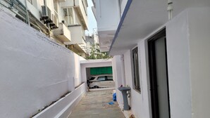Une ruelle étroite, avec un mur blanc d’un côté, un sol carrelé et l’entrée d’un immeuble dotée d’une fenêtre et d’une porte.