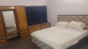 Une chambre à coucher avec un lit, une armoire, un miroir et un rideau.
