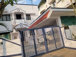 Il s’agit d’un immeuble résidentiel fermé, avec une façade blanche, un toit rouge et une porte de garage bien visible.