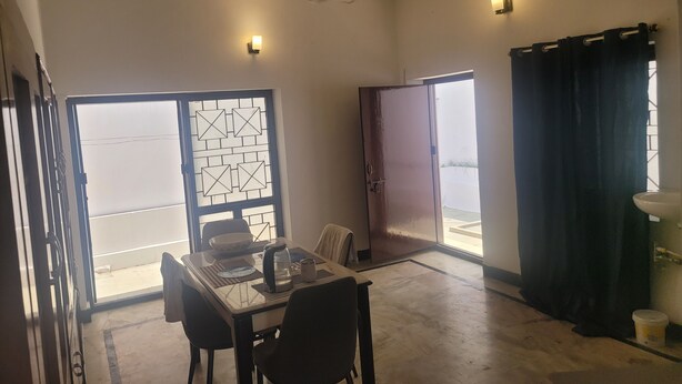 Une pièce comprenant une table à manger, des chaises, un ventilateur de plafond, une fenêtre avec vue et une porte.