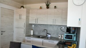 A compact kitchen with a sink, a microwave, and a coffee maker. There are cabinets above the counter and a clock on the wall. - Mobile Home With Terrace And Sea View (Pakostane)
