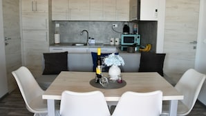 A modern kitchen with white cabinets, a dining table with white chairs, and a microwave on the counter. - Mobile Home With Terrace And Sea View (Pakostane)