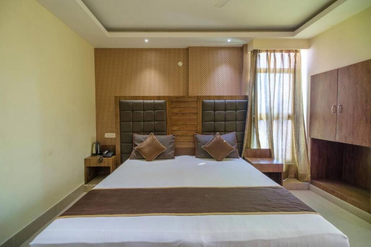 A large bed with a headboard, two bedside tables, a nightstand, and a wardrobe.
