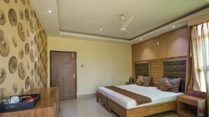 Un dormitorio con cama, mesitas de noche, cabecera de madera, ventilador de techo y una puerta.