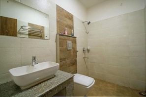 A bathroom with a white sink, a toilet, a shower, and a mirror. - Hotel Parnil Palace (Guwahati)