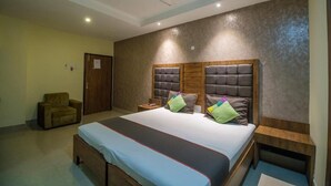 A bedroom with a bed, a chair, a bedside table, and a ceiling fan. - Hotel Parnil Palace (Guwahati)