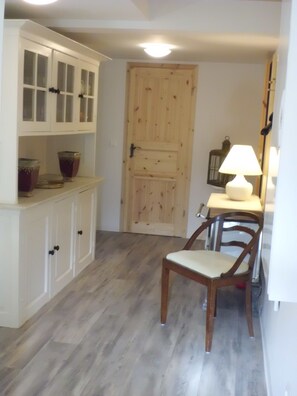 A room with a wooden door, a white cabinet with glass doors, a wooden chair, and a table with a lamp. - Charming 3-bedroom house in peaceful Dranske OT Gramtitz / island Ruegen (Dranske, OT Gramtitz)