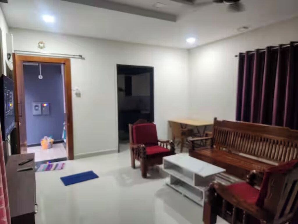 A living room with a sofa, chairs, a coffee table, and a television.