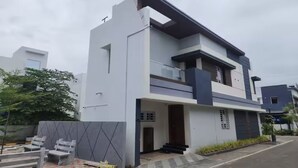 Ein modernes, zweistöckiges Haus mit Balkon, Eingangstür und kleiner Veranda.