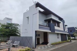 A modern two-story house with a balcony, a front door, and a small porch area.