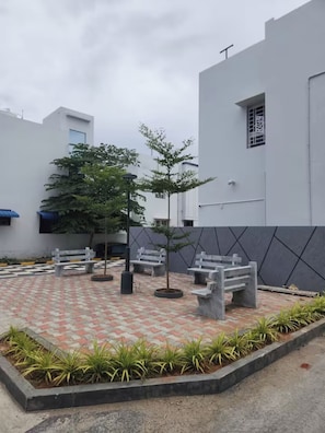 A courtyard with benches, potted plants, and a patterned floor.
