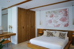 Ein modernes Schlafzimmer mit einem hölzernen Kopfteil, einem großen Bett mit gemusterten Kissen, einem Holzschrank und einem Schreibtisch mit einer Lampe.