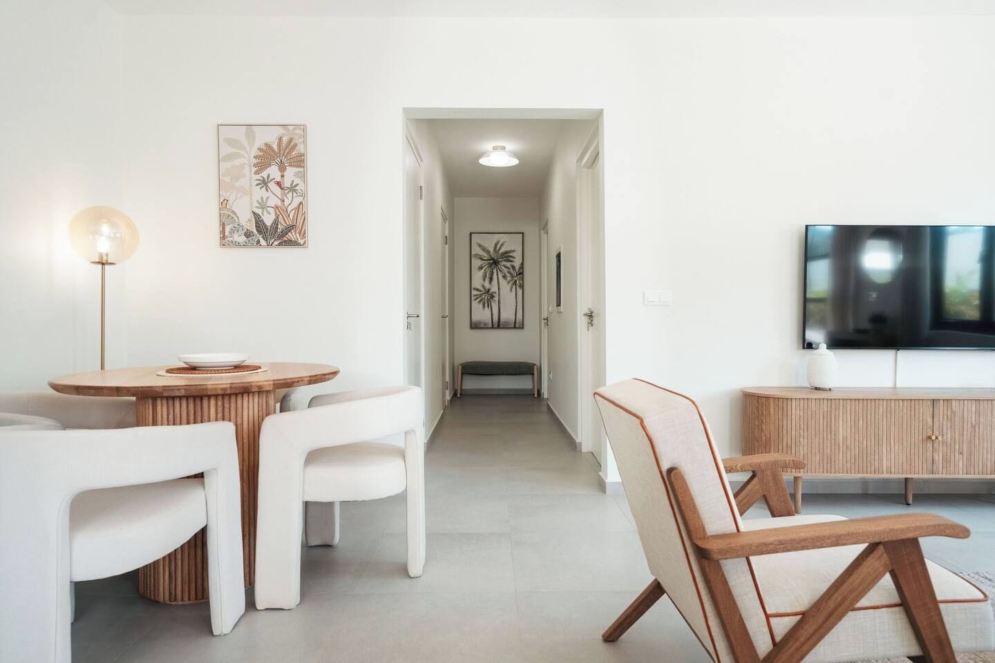 A modern living room with a dining area, a flat-screen TV, and artwork on the walls.