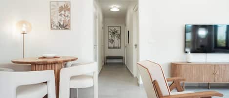 A modern living room with a dining area, a flat-screen TV, and artwork on the walls.