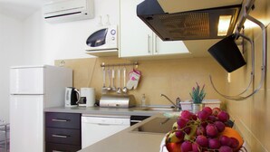 Cocina moderna con microondas, tostadora y lavamanos. Hay un cuenco de fruta sobre la encimera.