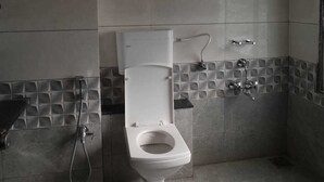 A bathroom with a toilet, shower, and a towel rack. - Hotel Royal King (Vadodara)