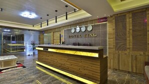 A reception desk with a 'ROYAL KING' sign, a clock, and a CCTV surveillance sign. - Hotel Royal King (Vadodara)