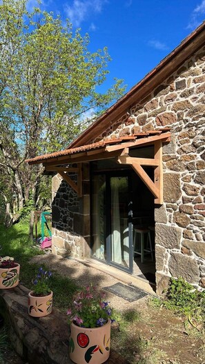 Un bâtiment en pierre doté d’un porche en bois et d’une porte en verre.