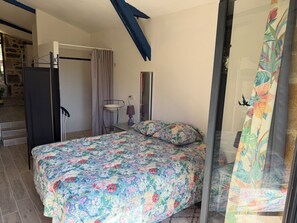 A bedroom with a bed, a desk, a chair, a window with curtains, and a staircase leading to an outdoor area. - QUIET LOFT IN THE COUNTRYSIDE, 7 KM FROM AMENITIES (Saint-Bressou)