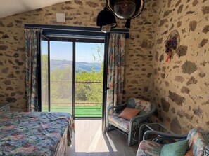 A room with a bed, a chair, and a view of a green landscape through a glass door. - QUIET LOFT IN THE COUNTRYSIDE, 7 KM FROM AMENITIES (Saint-Bressou)