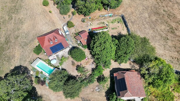 An aerial view of a residential area with multiple houses, a swimming pool, and a solar panel installation. - QUIET LOFT IN THE COUNTRYSIDE, 7 KM FROM AMENITIES (Saint-Bressou)