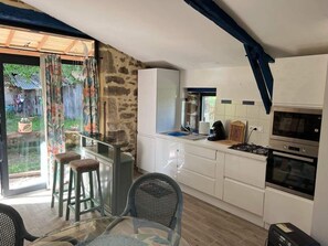 A compact kitchen with a dining area, a large window, and a view of the outside. - QUIET LOFT IN THE COUNTRYSIDE, 7 KM FROM AMENITIES (Saint-Bressou)