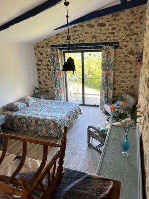 Une chambre à coucher avec un lit, un bureau et une chaise. Il y a une fenêtre avec des rideaux et une vue sur la verdure à l’extérieur.