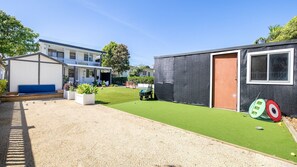 Ein Wohnhaus mit überdachter Terrasse, einem kleinen Garten mit Rasen und einer Garage.